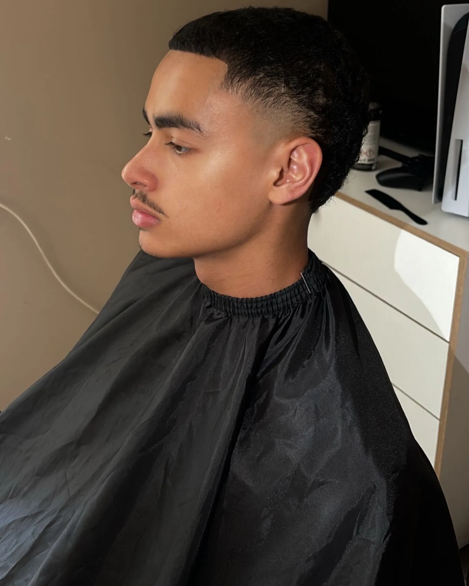 Side view of a sharply lined-up hairline, with a low taper fading into the skin at the temple.