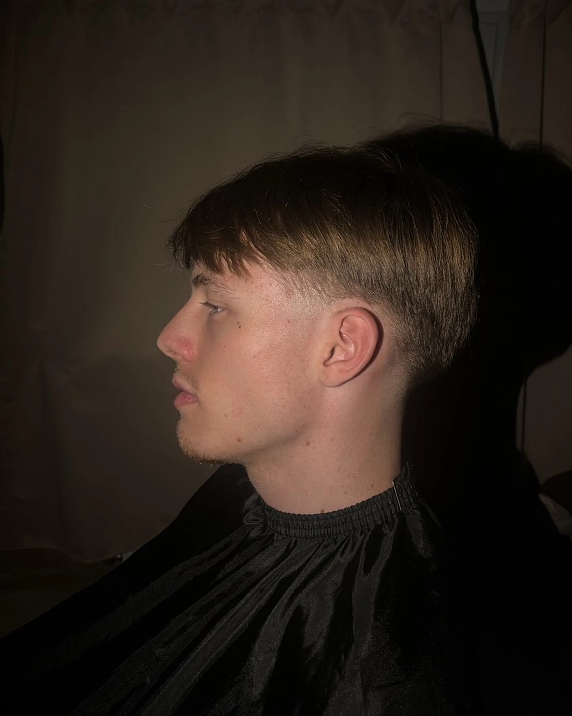 Coupe texturée avec une frange droite et un dégradé bas sur le côté.